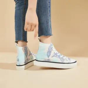 A woman stands on a beige background wearing Hot Sale Zapatos women’s casual blue print canvas sneakers, which feature lace-up design and are customizable for OEM/ODM orders.