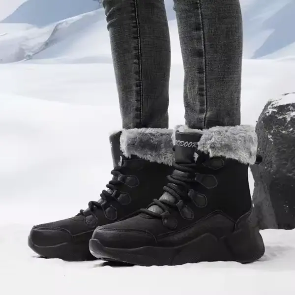 A person wearing OEM ODM Source Factory Winter Waterproof Anti-slip Warm Snow Boots Women's Solid PU Cotton Shoes and dark jeans stands on snow with mountains in the background.