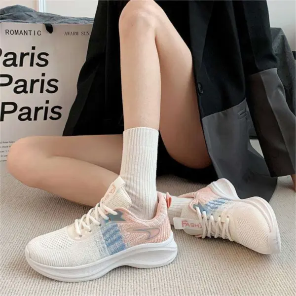 A person sits on the floor wearing a black jacket, white socks, and Factory Custom Spring New Styles Sports Sneakers—chunky, non-slip, height-increasing women’s shoes with blue and pink accents. A large “Paris” shopping bag is in the background.