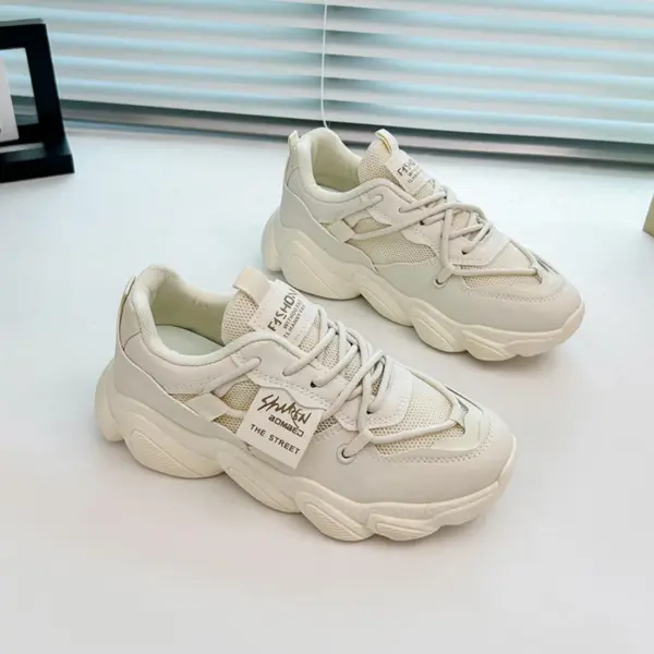 A pair of Women's Sneakers Low Top Mesh Thick Sole Height Increasing Wear Resistant Outdoor Sports Shoes, in white with side text details, are displayed on a white surface near a window.
