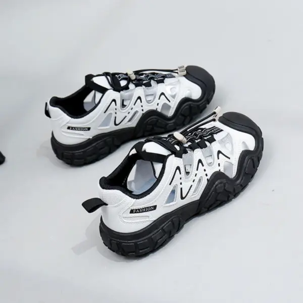 A pair of Factory Wholesale Hot Selling Thick Soled Sports Sneakers for women, featuring breathable mesh and PU, in white and black with metallic lace locks, displayed on a light gray surface.
