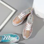 Two pairs of wholesale round toe unisex tie dye canvas shoes for women, featuring artistic pastel designs, are displayed on a gray surface beside white and gray geometric decor.