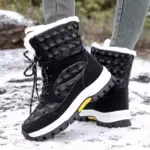 A person stands on a snowy surface wearing 2024 Customized LOGO Pattern Style Autumn Winter Trendi Warm Snow Boots with mixed PU and cotton, featuring black uppers, white soles, and faux fur lining.