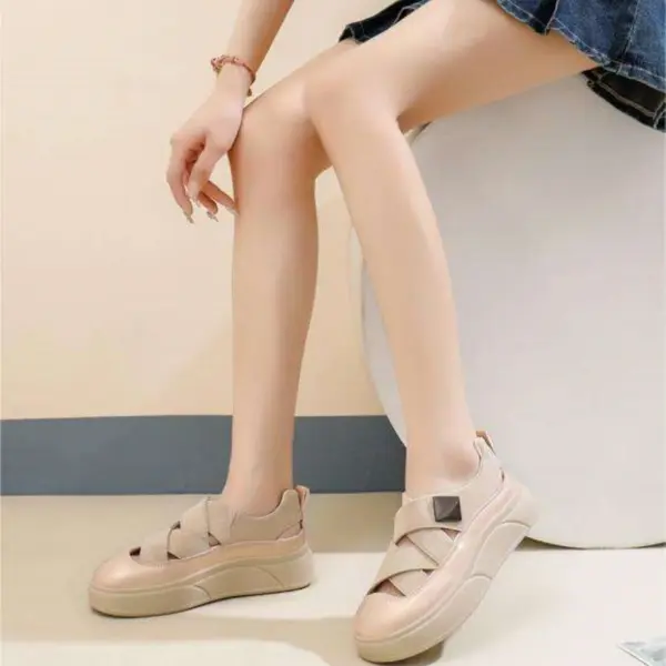 A person wearing 2024 OEM ODM PU hollow skateboard outdoor walking shoes summer wear resistant mesh women's sandals with crisscross straps and a denim skirt sits on a white rounded seat against a light background.