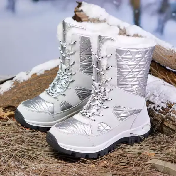 A pair of Wholesale Mountain Outdoor Hiking Wear Resistant Women's Snow Boots with TPR EVA thick soles and cotton lining, in silver and white, are set on pine needles and logs with snow in the background.