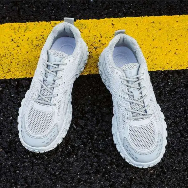 A pair of OEM Trendy Tire Sole Men Shoes—light, anti-slip, wear-resistant sneakers with cotton mesh and EVA—is placed side by side on black asphalt with a thick yellow line running underneath.