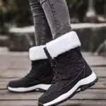 A person wearing gray skinny jeans and OEM Factory High Top Breathable Warm Cotton Snow Boots for women with white faux fur lining stands on a wooden surface outdoors—ideal for highlighting winter footwear designs in real-life settings.