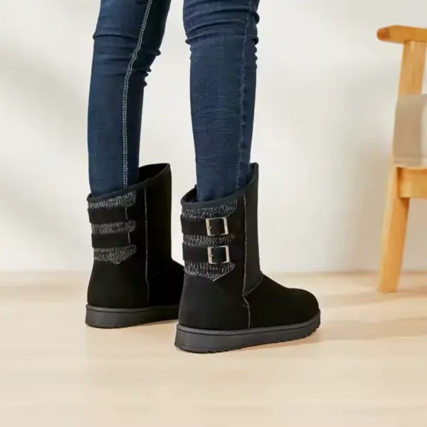 A person in dark skinny jeans and black Wholesale Fashion Western Designer Snow Boots for Women 2024 stands on a light wooden floor next to a wooden chair.