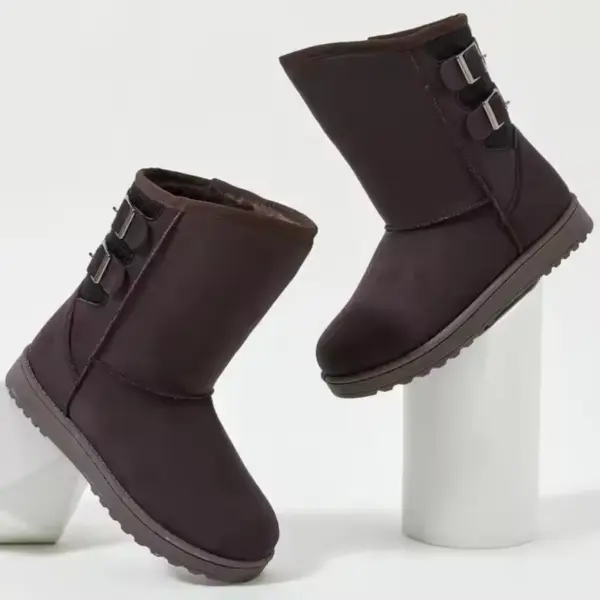 A pair of Wholesale Custom Designer Winter Snow Boots for women with side buckles, shown on white cylindrical stands against a plain background.