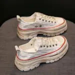 A pair of WomenS Casual Walking Style Canvas Shoes Chunky Shoes for Women, featuring white distressed canvas, thick beige soles, and red details, are displayed side by side on a gray fabric surface.