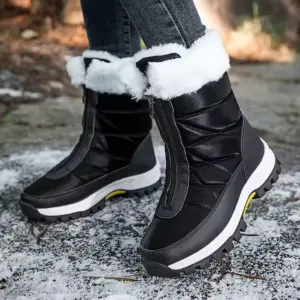 A person wears Wholesale Custom Winter Trendy Waterproof Snow Boots with plush lining and zipper, standing on a lightly snow-dusted ground—ideal for highlighting large-size OEM ODM outdoor women's footwear designs.