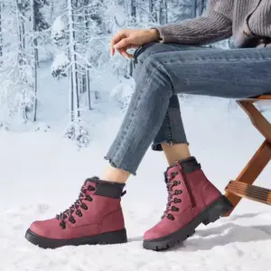 A person sits on a wooden chair in snowy outdoors, wearing blue jeans, a gray sweater, and Wholesale Ankle Boots Snow Weather for Women Leather Zipper Casual Waterproof Winter Plush Boots for Men. Snow-covered trees are visible in the background.