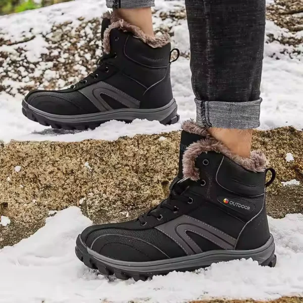 A person in Factory Warm Anti slip Breathable Snow Boots, wear-resistant rubber winter lace-up men's shoes, with fur lining, stands on snow-covered ground and rocks.