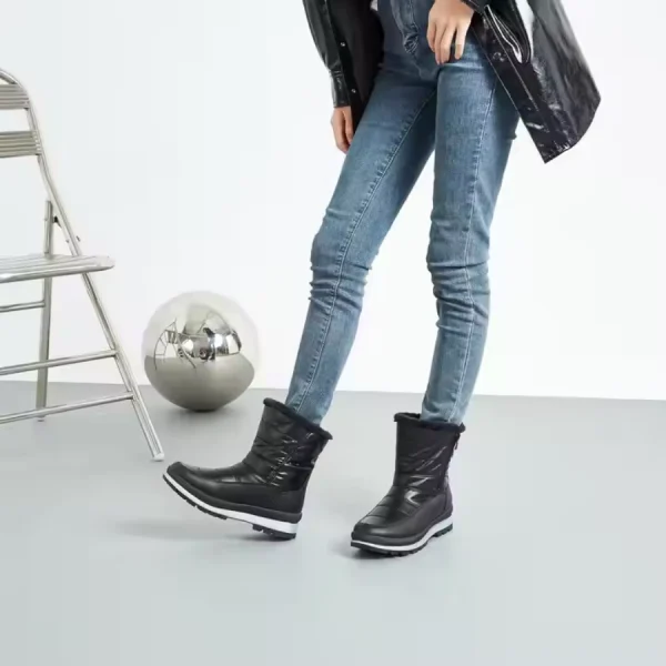 A person in blue jeans and black Wholesales Warm Snow OEM Custom Ankle Snow Leather Boots Furry Boots for Women stands near a folding chair and reflective sphere, highlighting the versatility of these women's fur boots in a minimal indoor setting.