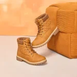 2025 Winter Snow Ankle Boots for men and women, featuring high heels and platforms, are displayed beside a matching corduroy ottoman against a peach background—available for wholesale, OEM, and ODM orders.